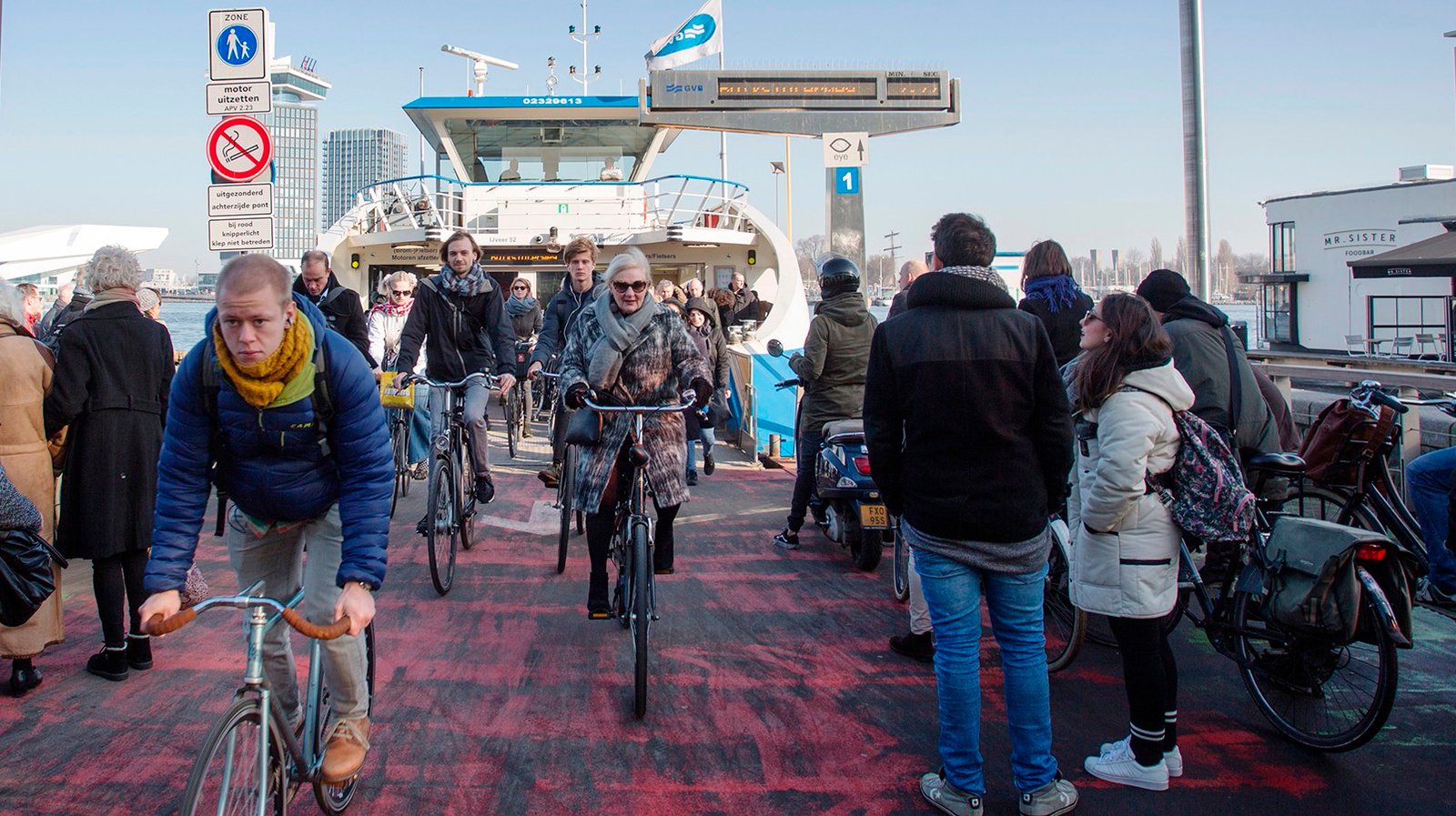 Beaumont - Bas de Meijer - In Amsterdam verlaten fietsers en voetgangers het pontje over het IJ, terwijl een nieuwe groep passagiers al staat te wachten.